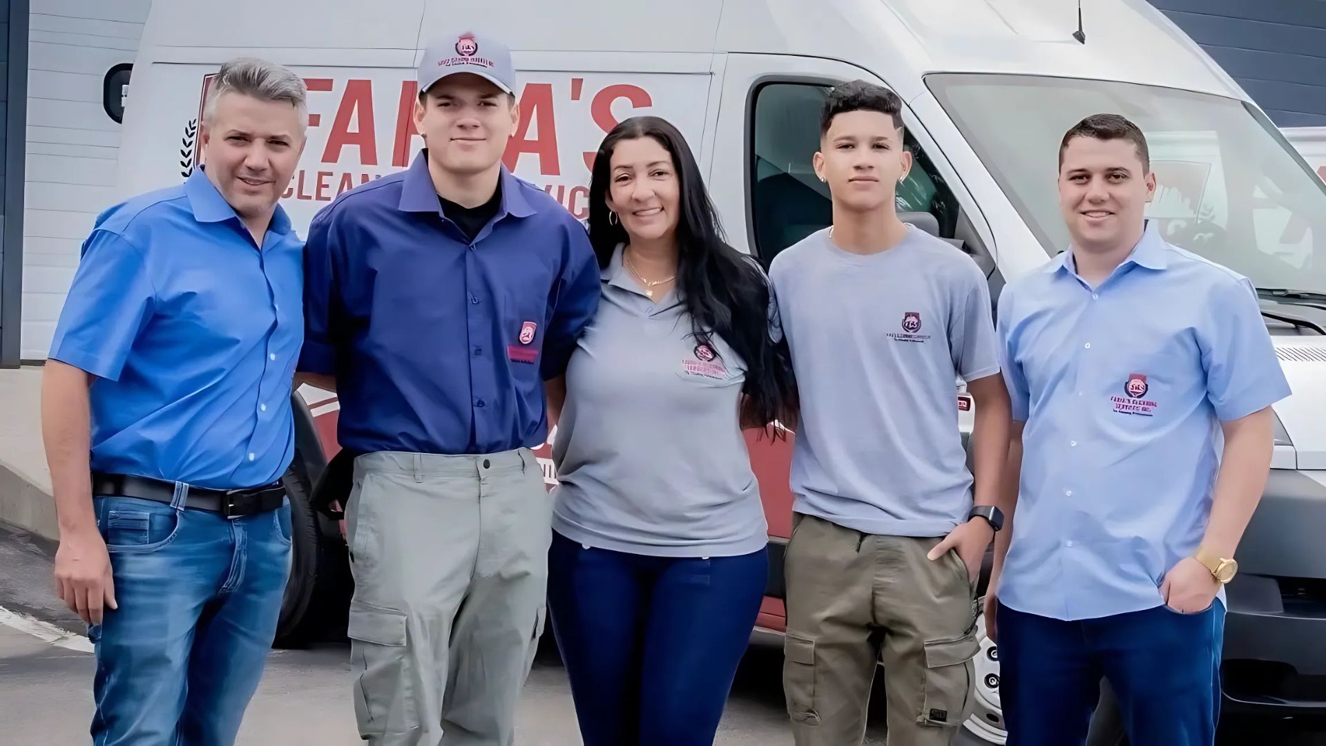 A group of five people stands in front of a van with "TAMA'S CLEANING" on it. They are smiling and wearing matching shirts with a logo. The van is white and parked on a concrete surface.